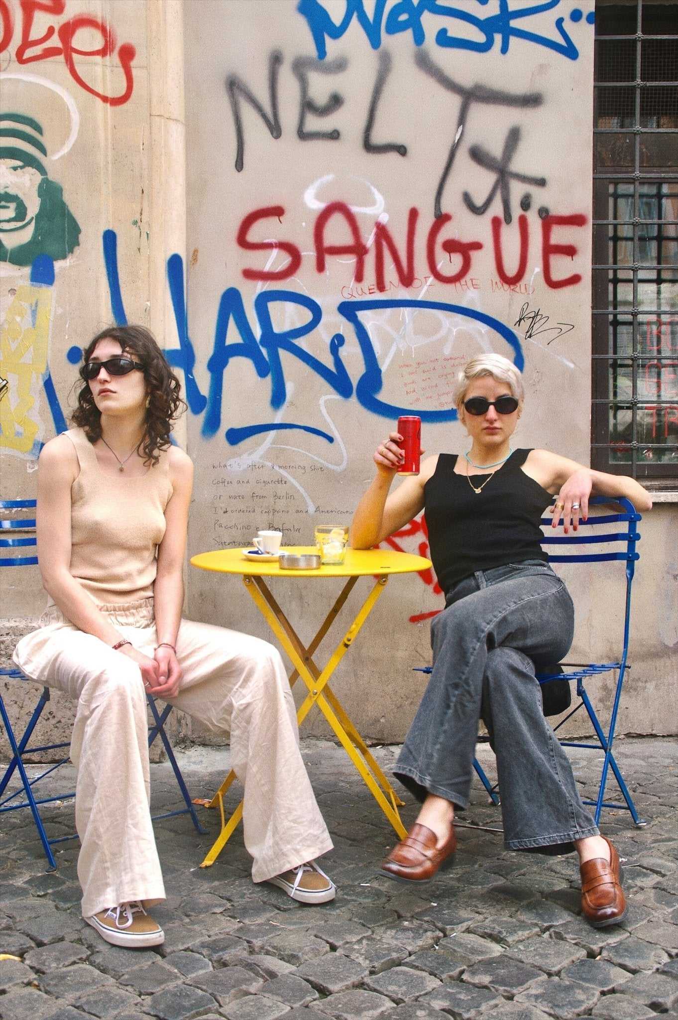 Margaret Tank Top - Sustainable Lyocell Tank Top in black and beige worn by two women seated at a yellow café table, styled with flared pants.