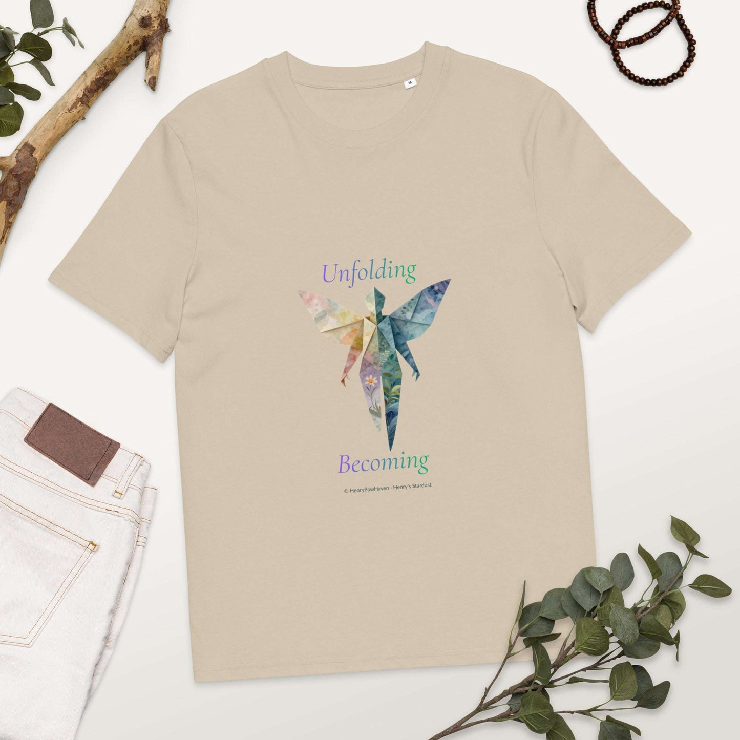 BOMBY Unfolding origamis silhouette Organic Cotton T-Shirt in beige featuring colorful butterfly-winged silhouette and 'Unfolding Becoming' text.