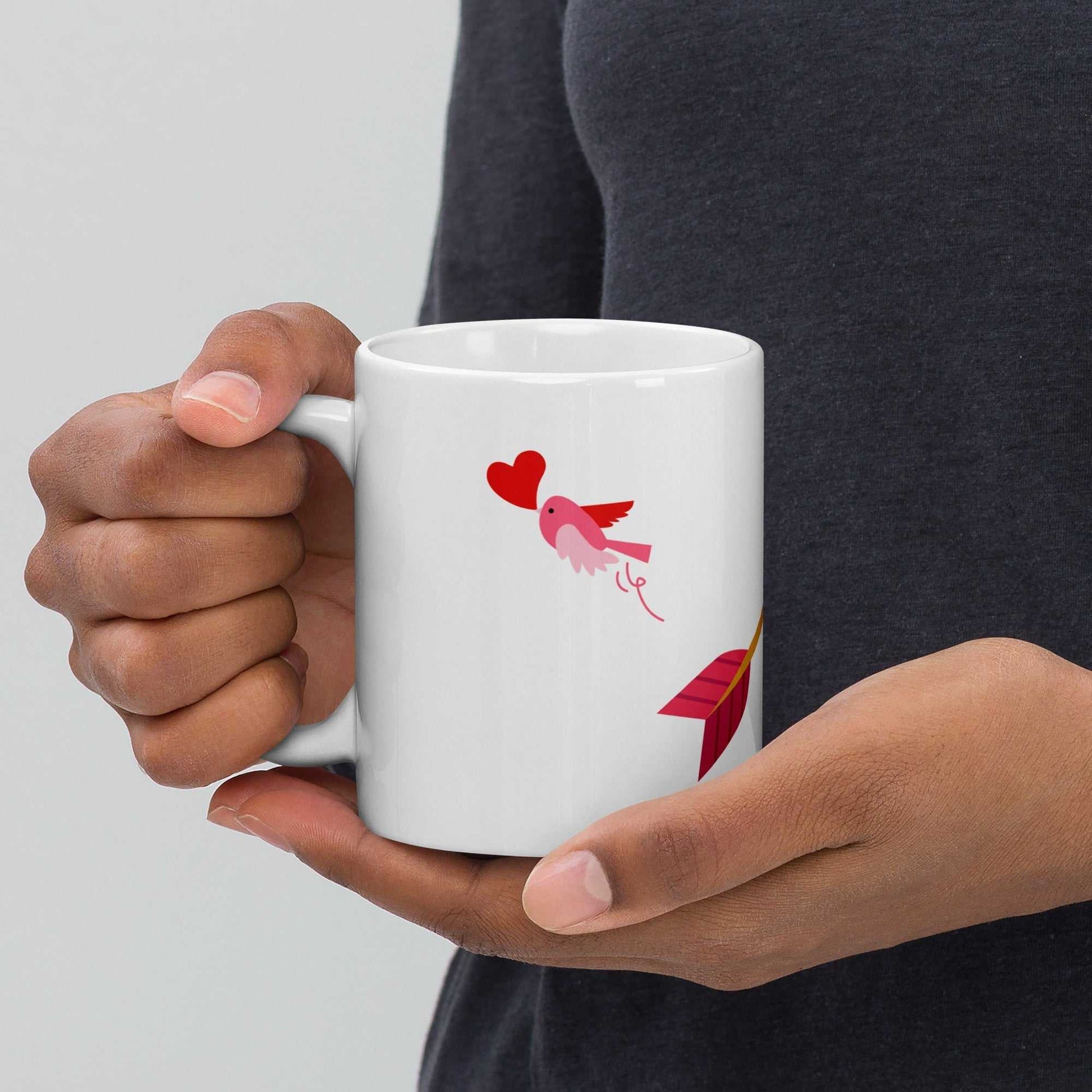 Valentine mug gift with pink bird and arrow design, held in hand to show size and romantic style for gifting.