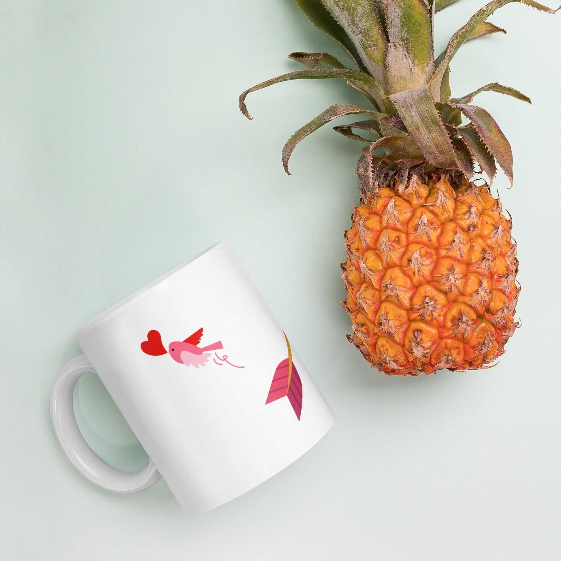 Valentine mug gift with pink bird and heart arrow design next to pineapple, playful and romantic 11 oz ceramic mug.