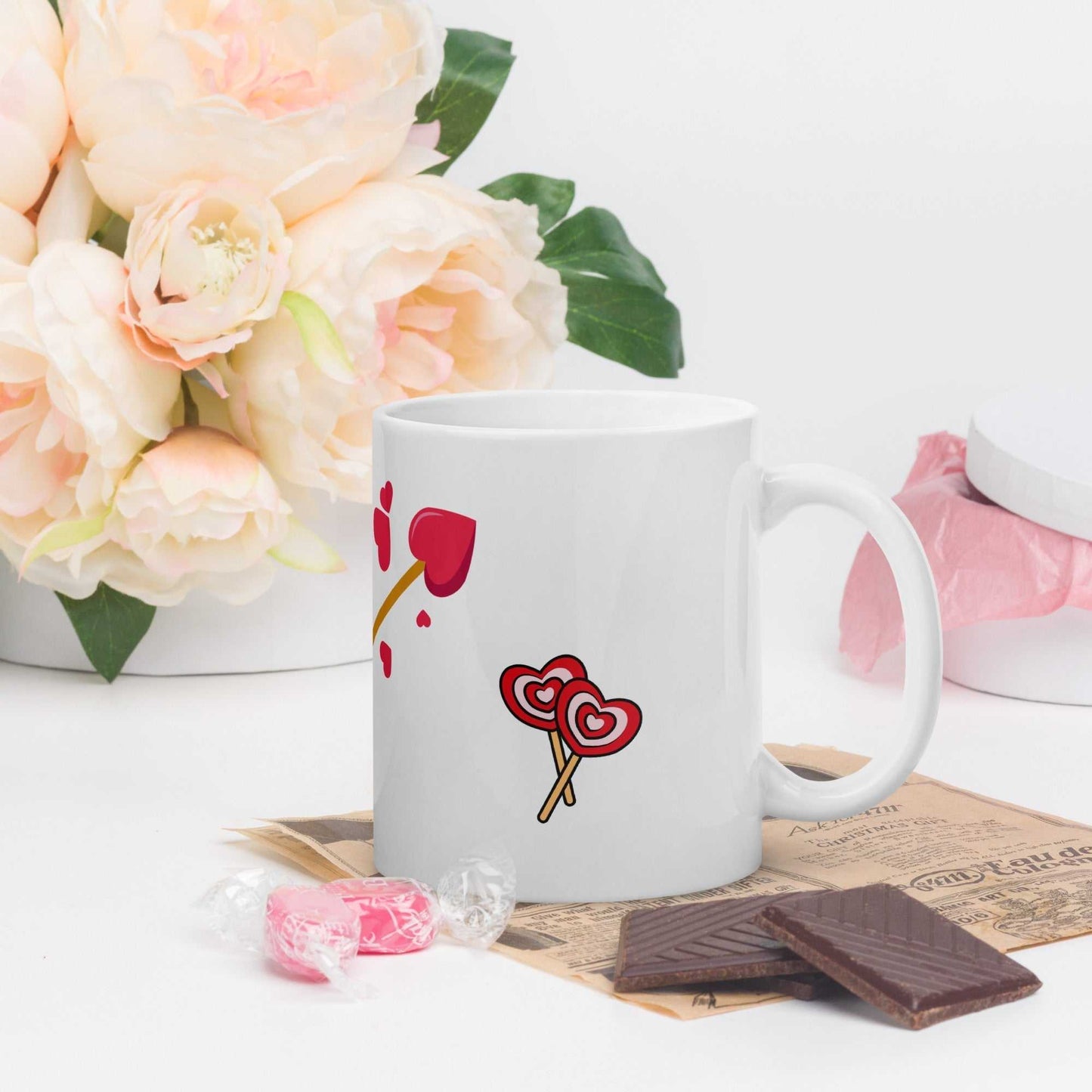 Valentine mug gift with heart lollipops and arrow design, styled with chocolates and flowers for a sweet gift presentation.