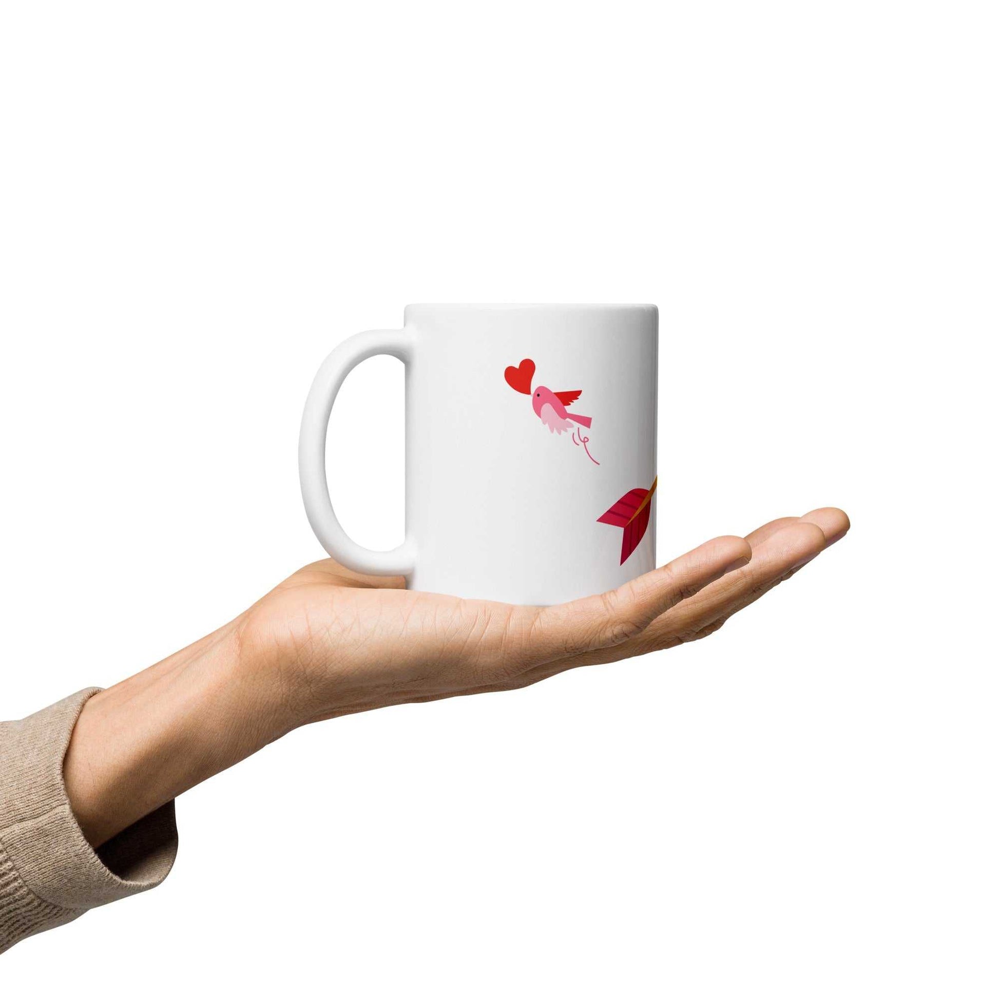 Hand presenting Valentine mug gift with pink bird and heart arrow design, 11 oz ceramic mug for Valentine's Day.