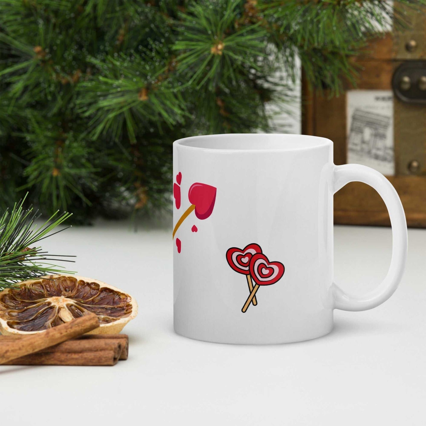 Heart-themed Valentine mug gift with lollipop and arrow design, placed in a holiday-inspired kitchen setting.