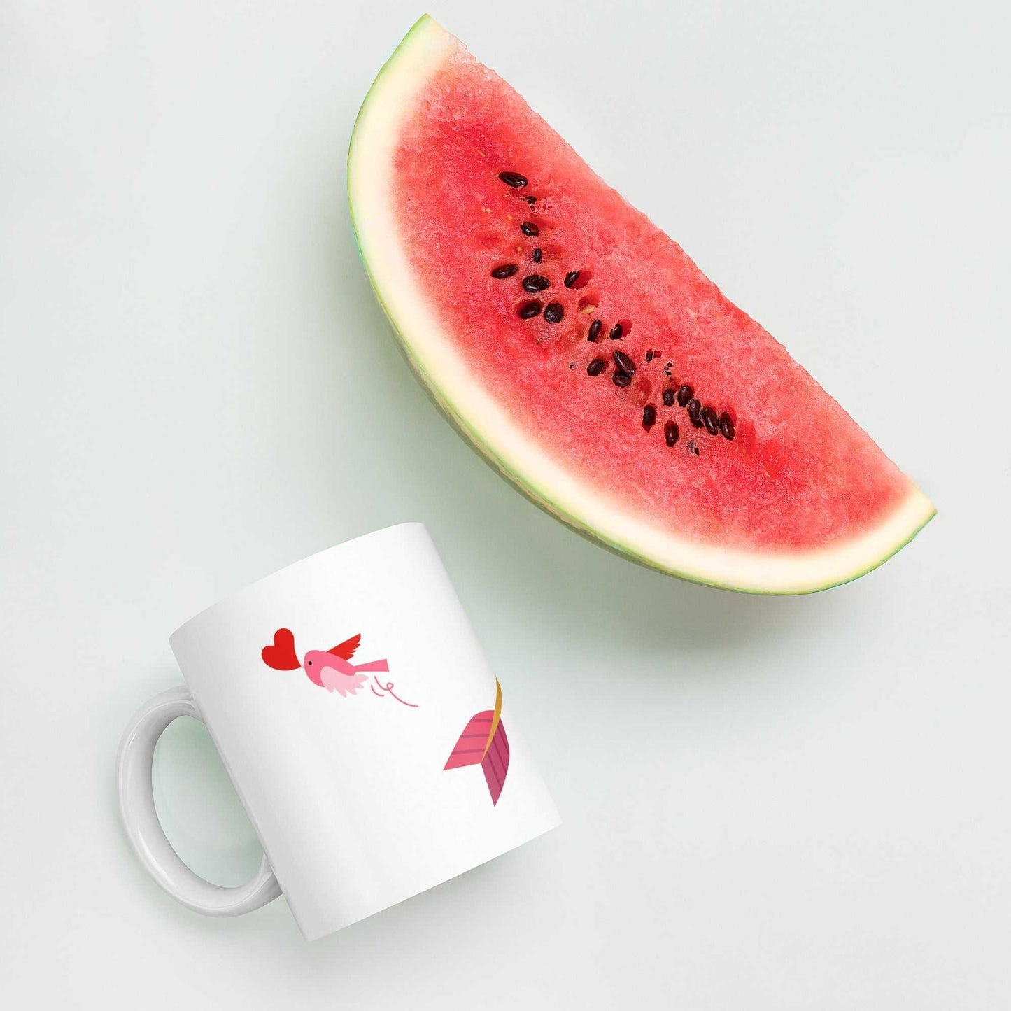 Valentine mug gift with arrow, lollipops, and bird design placed beside a watermelon slice, ideal for romantic kitchen decor.