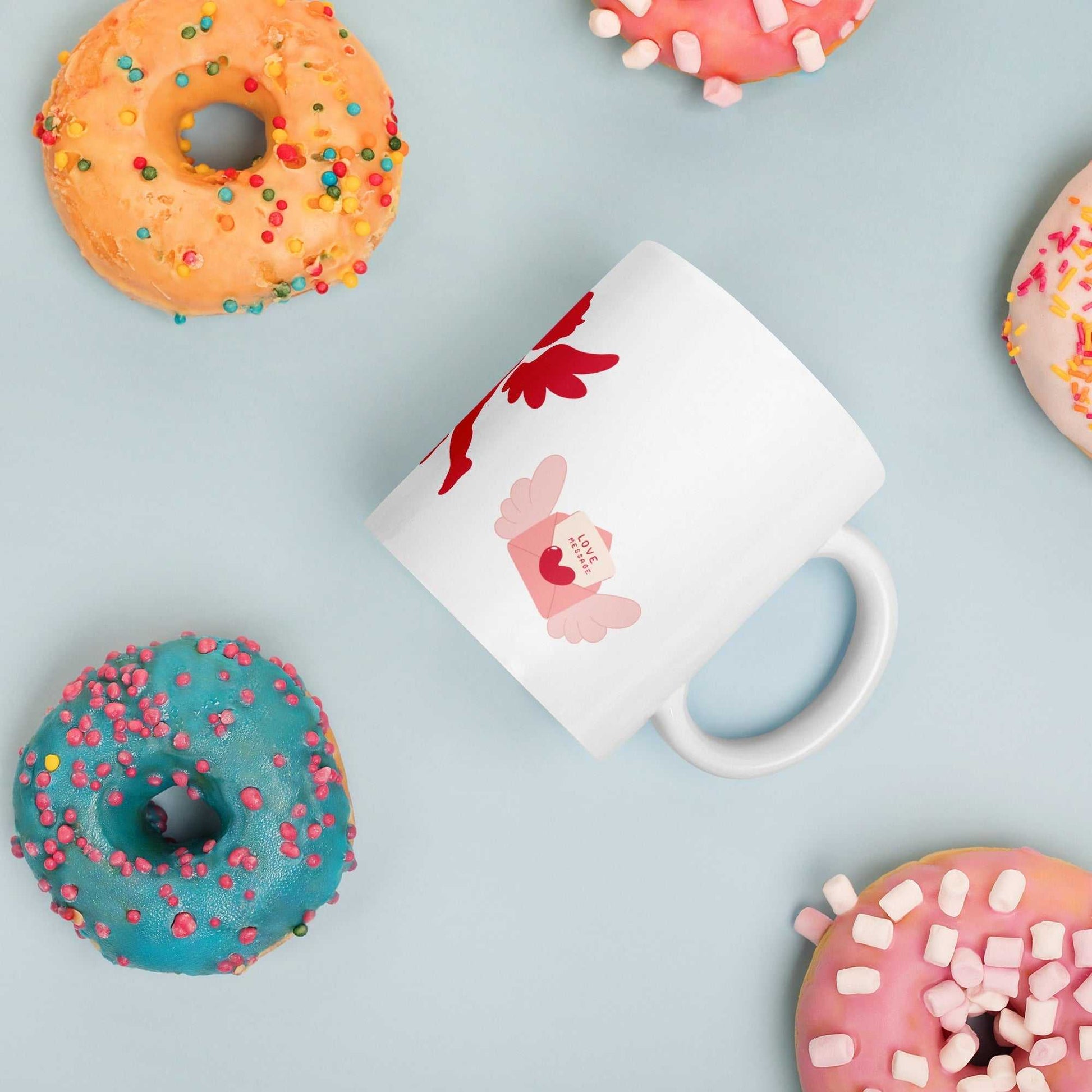 Valentine Mug - Cupid & Butterfly with winged envelope, ceramic 11 oz mug surrounded by colorful donuts for festive gifting.