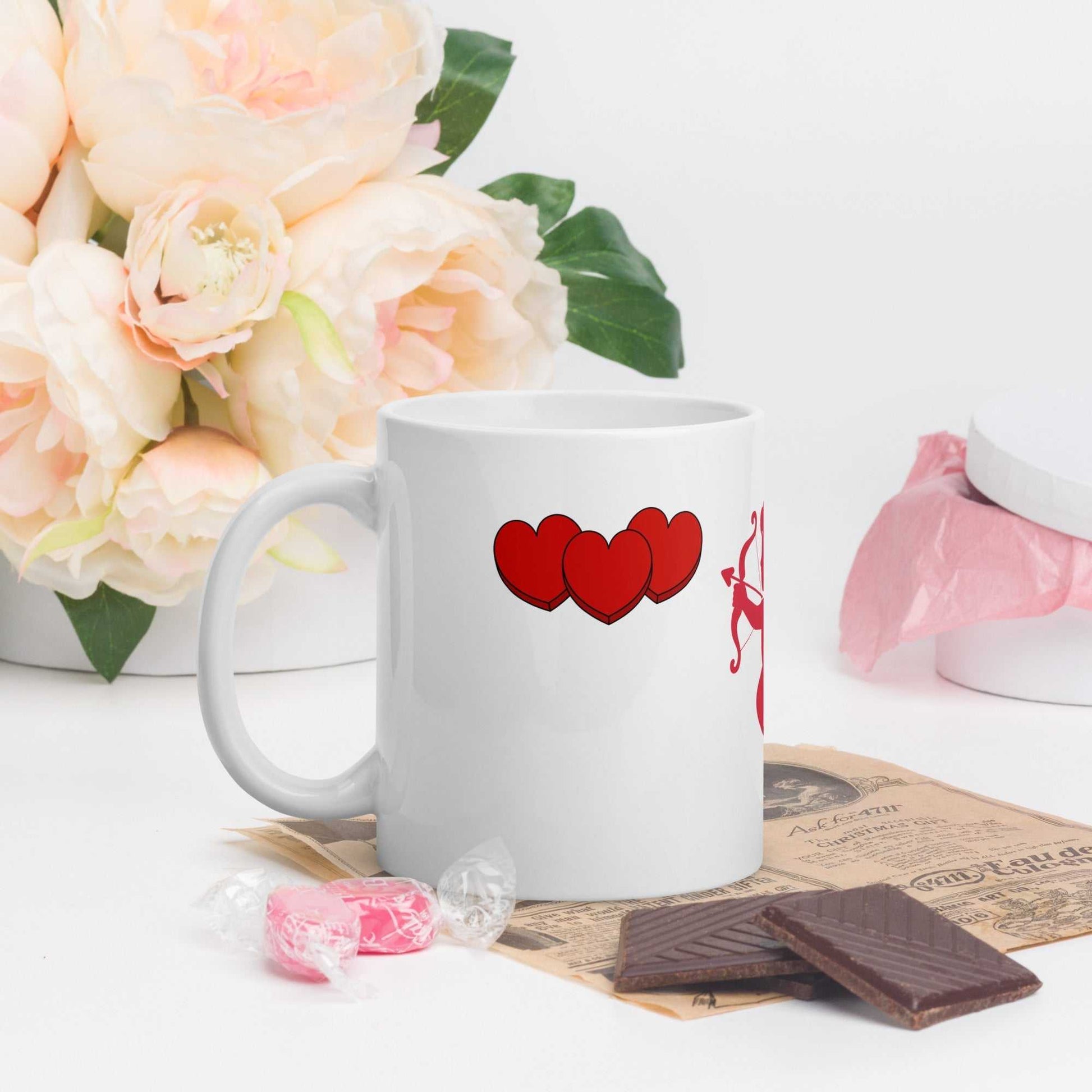 Valentine Mug - Cupid & Butterfly with triple heart design, 11 oz ceramic mug styled with chocolates and flowers for gifting.