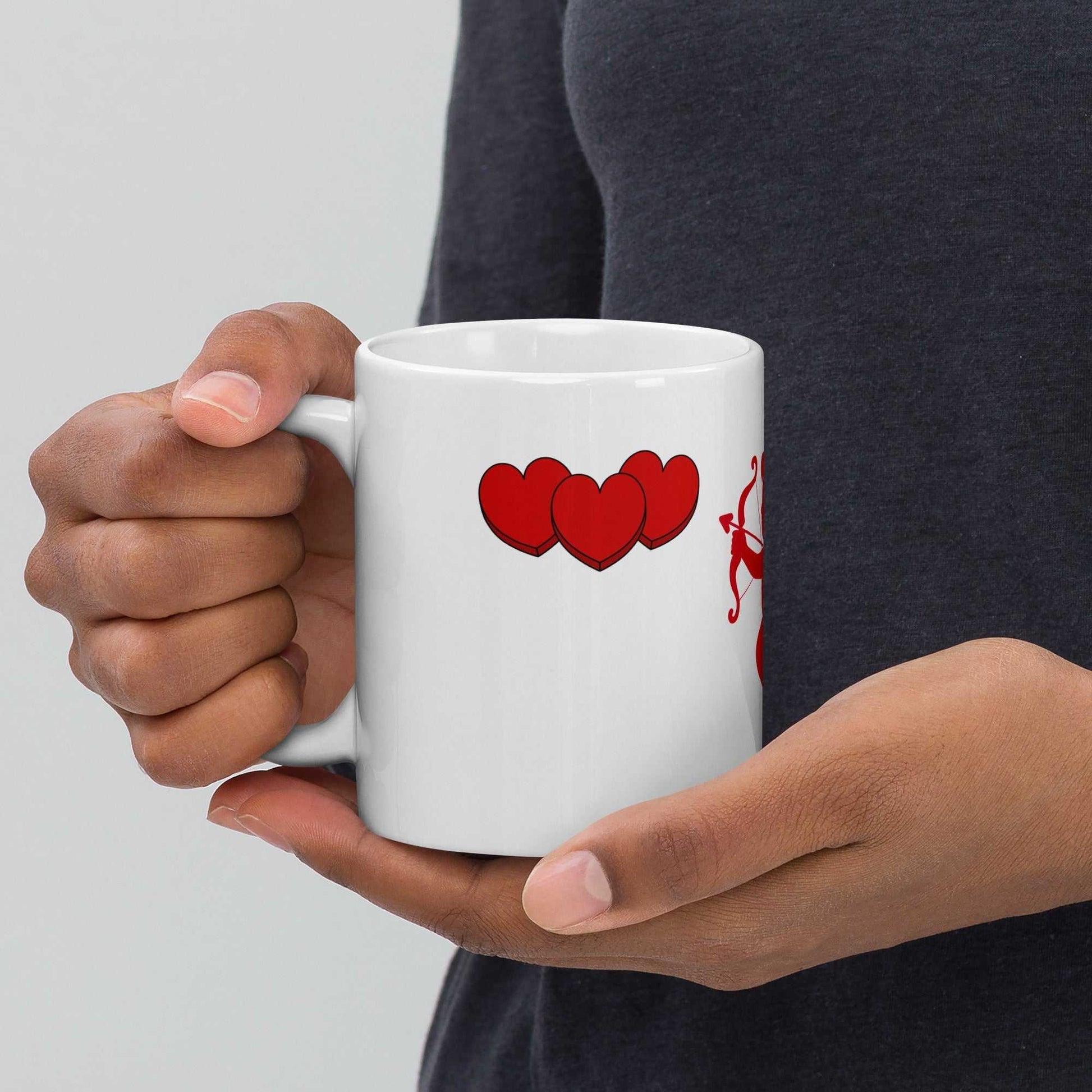 Hands holding Valentine Mug - Cupid & Butterfly gift featuring red hearts. Ceramic 11 oz mug for Valentine's Day coffee or tea lovers.