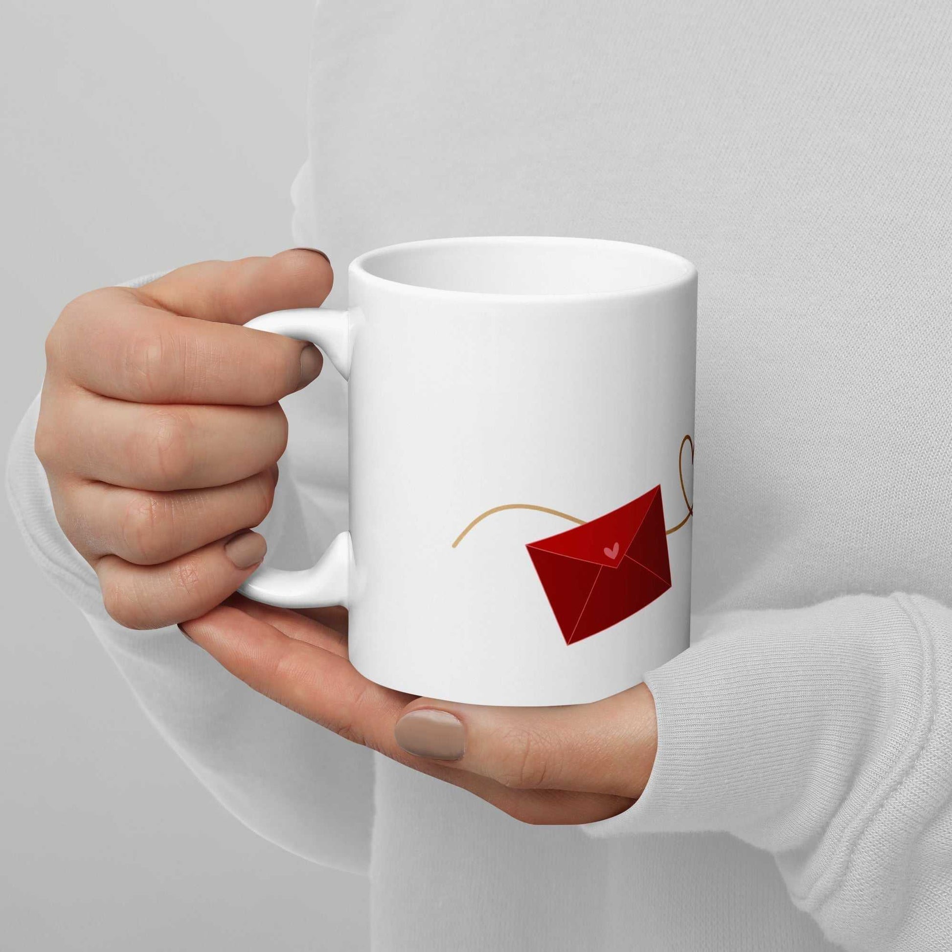 White ceramic valentine mug with red envelope graphic, held in hand, perfect for romantic gifting and daily use.