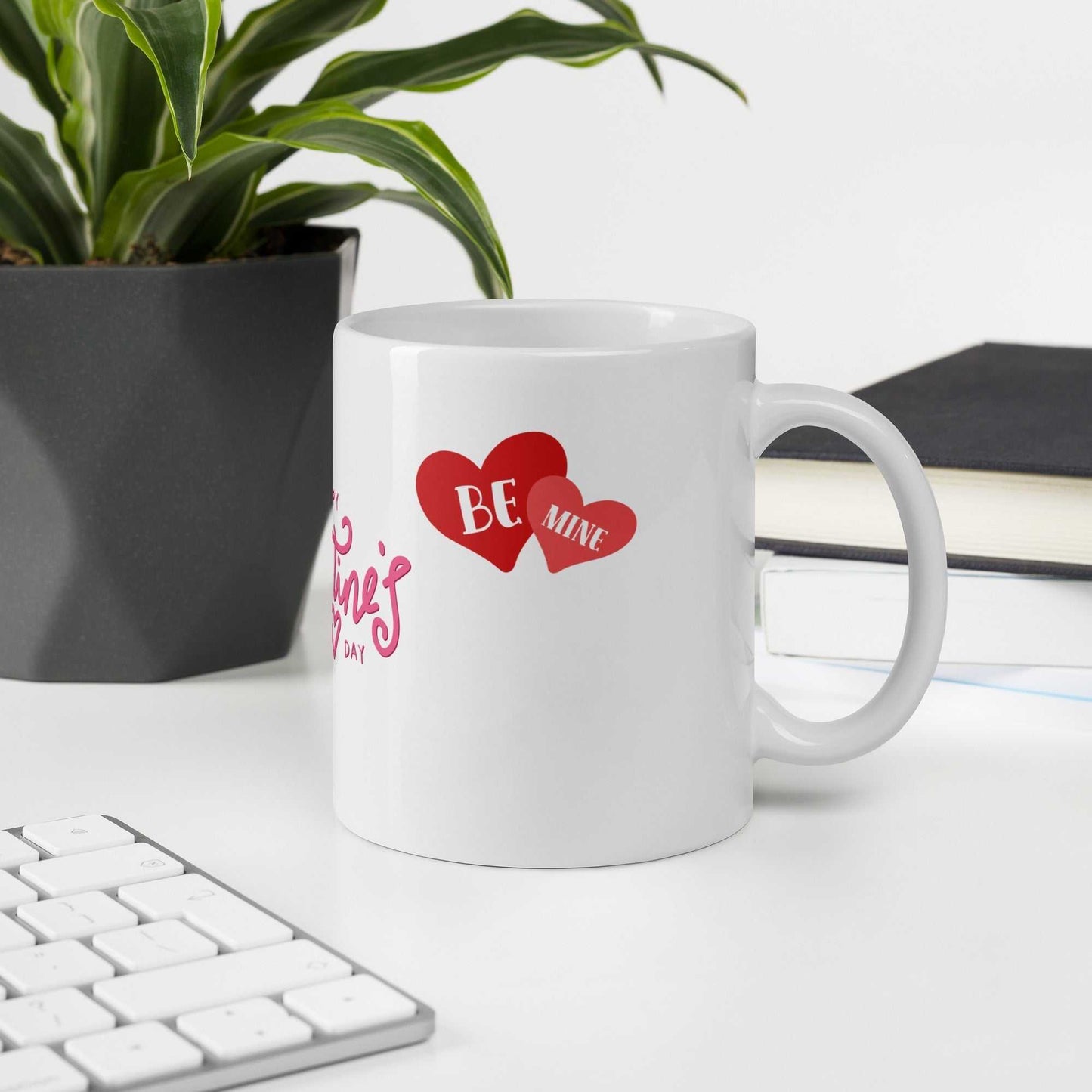 Valentine Mug - valentine mug | 11oz ceramic drinkware with 'Be Mine' heart design, placed on office desk near plant and keyboard.