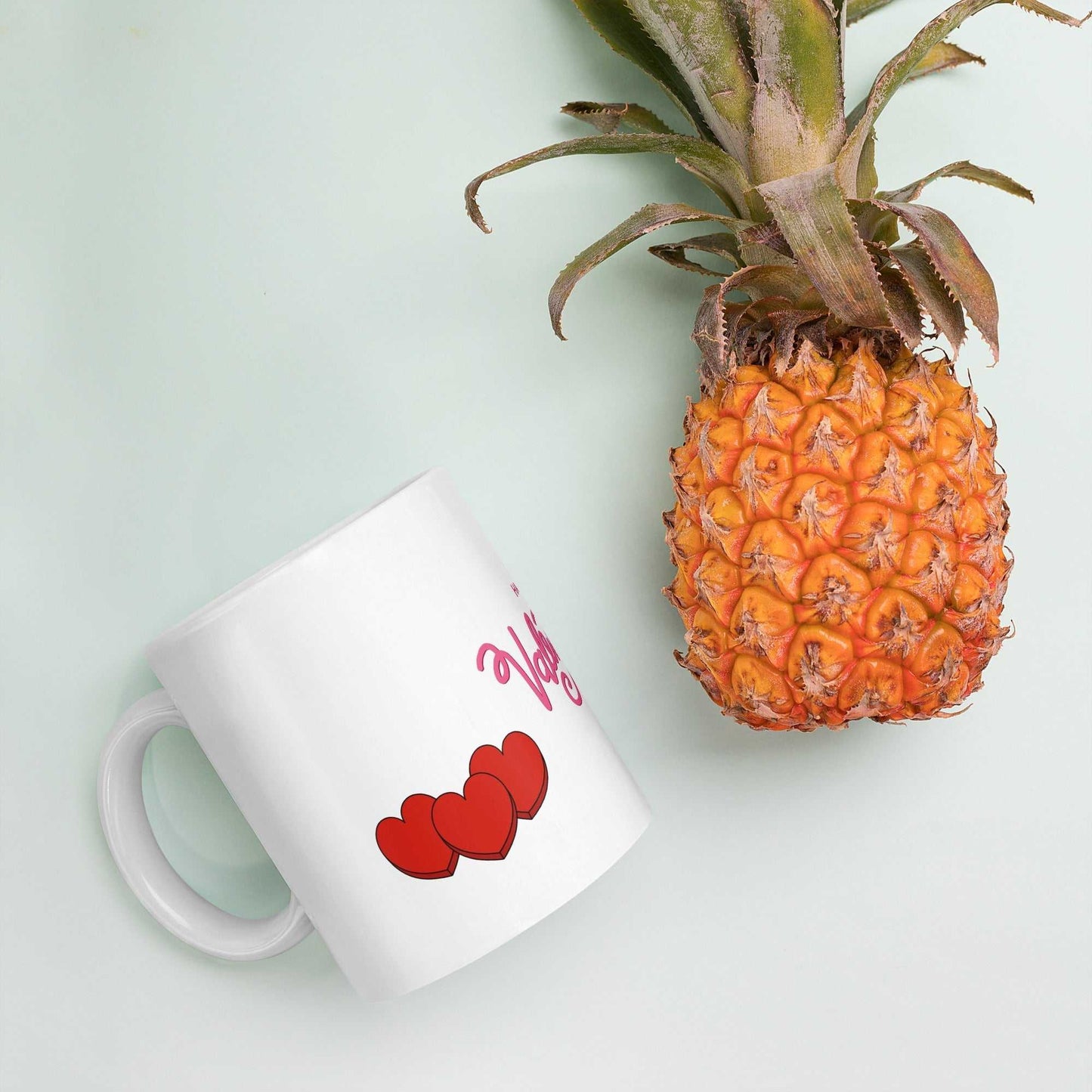 Valentine Mug - valentine mug | 11oz ceramic drinkware with red hearts, placed beside pineapple, fun and tropical gift idea.