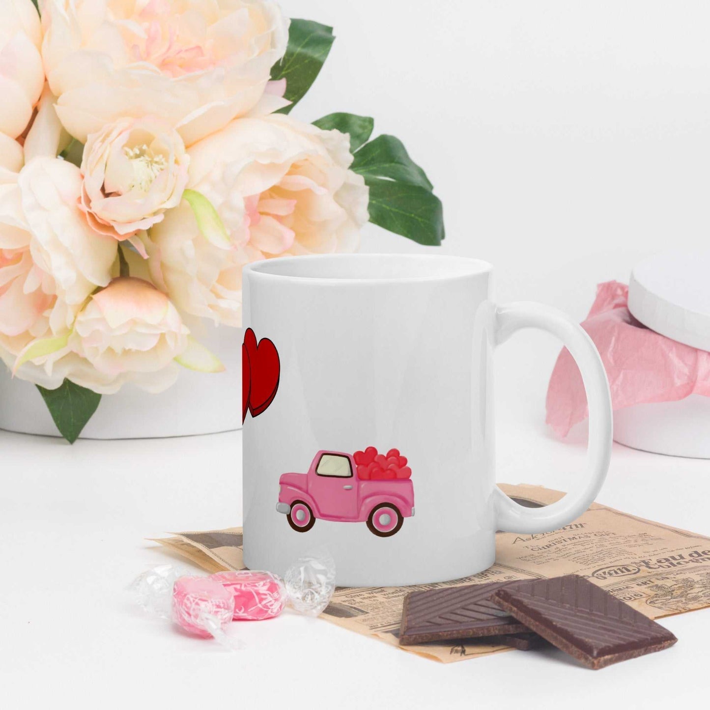 Valentine mug with pink truck and hearts design, styled with chocolates and flowers, ideal for romantic home decor.
