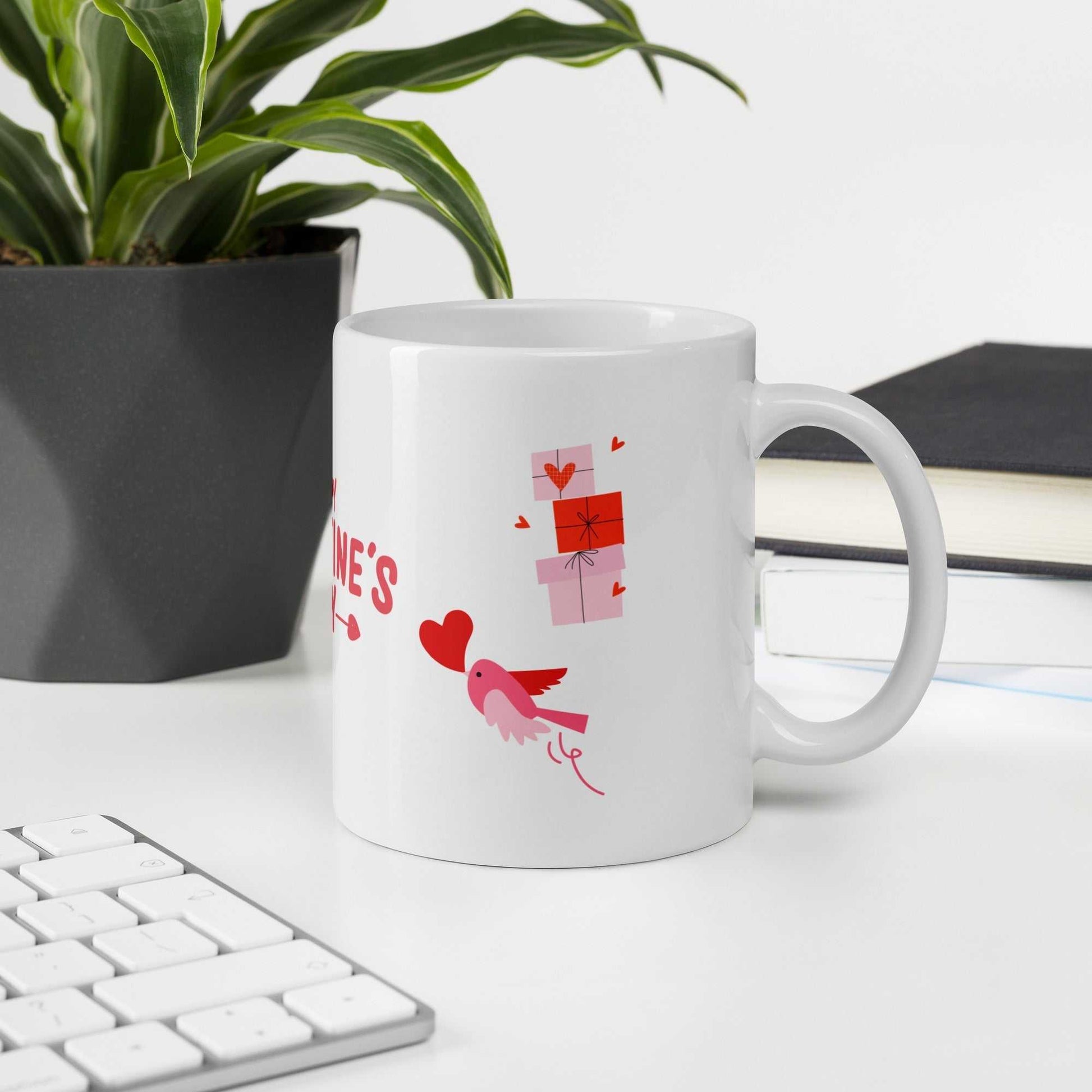 Valentine mug with bird and gift boxes on desk beside plant and books. Ideal for office gifting.