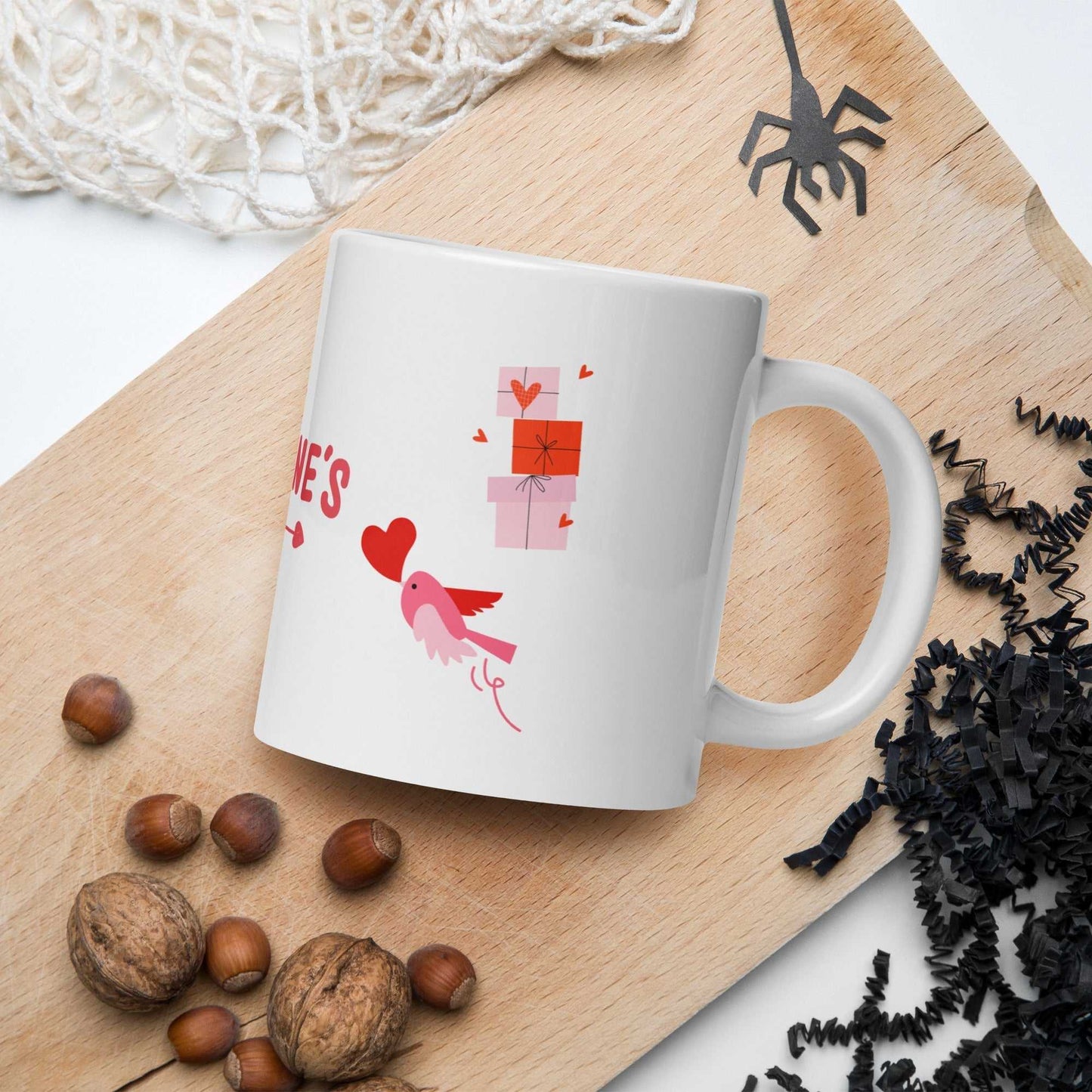 Ceramic valentine mug featuring a pink bird holding a heart with stacked gift boxes; ideal for Valentine's Day celebrations.