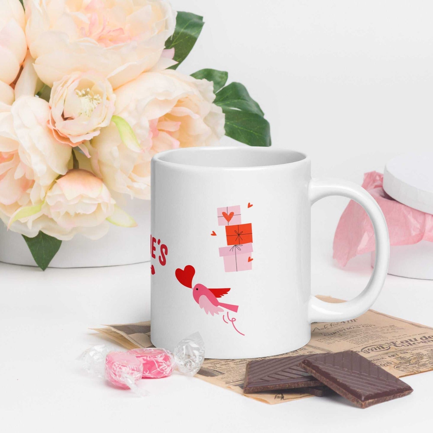Valentine mug with bird and heart design, paired with chocolates and pink roses; dishwasher safe ceramic.