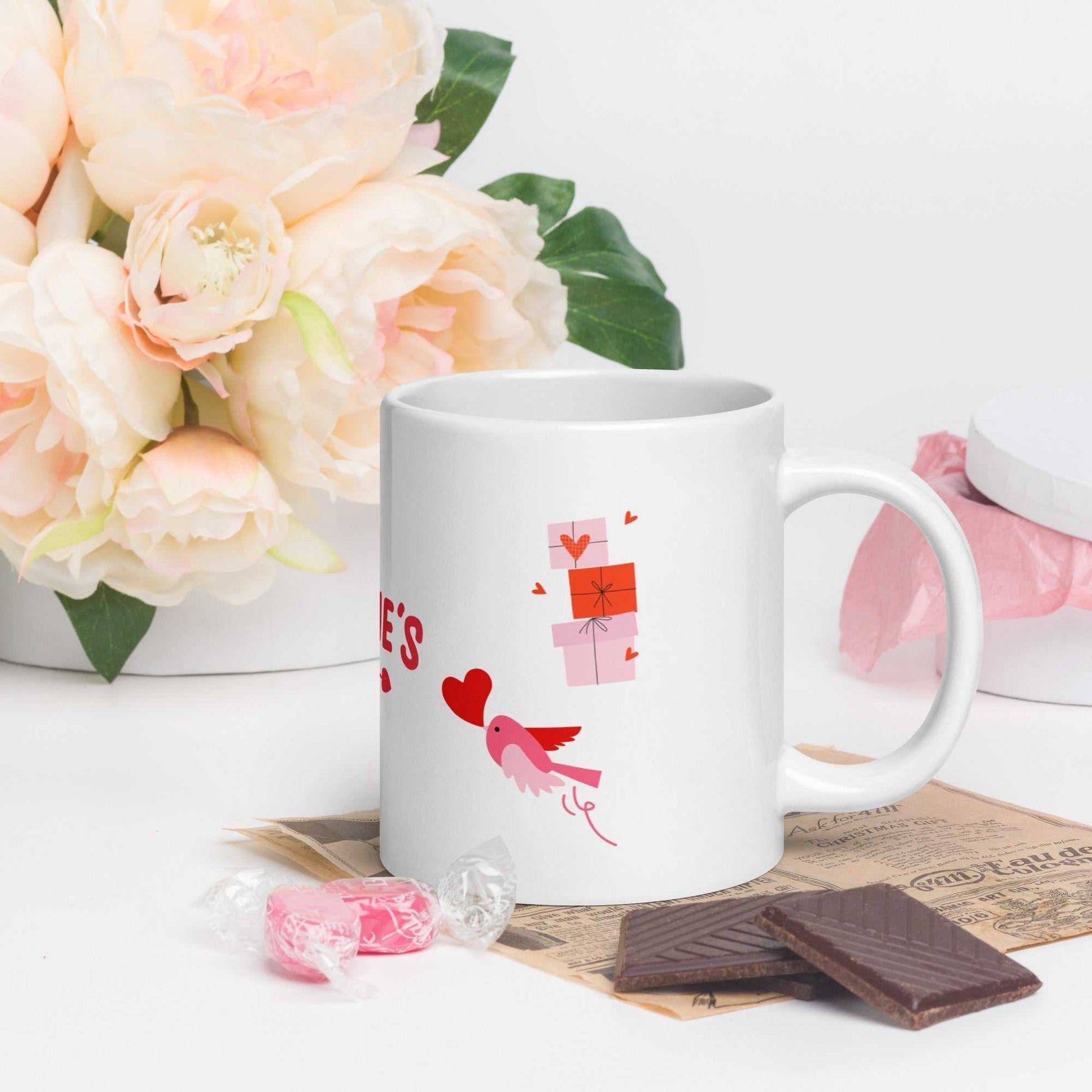 Valentine mug with bird and heart design, paired with chocolates and pink roses; dishwasher safe ceramic.