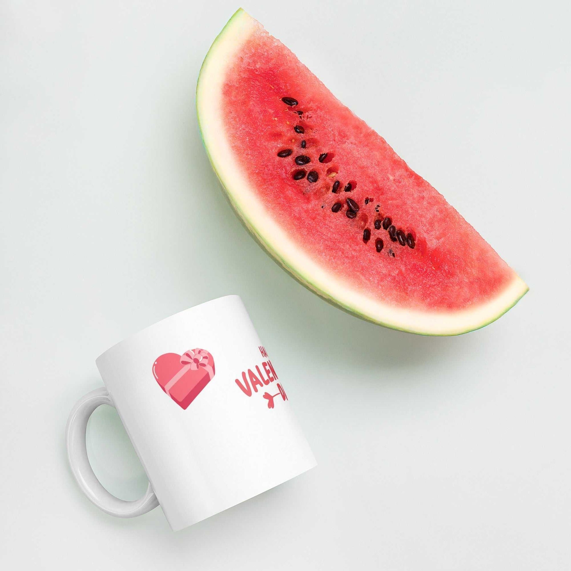 Valentine mug with heart gift box beside a watermelon slice. Bright and cheerful ceramic mug gift.
