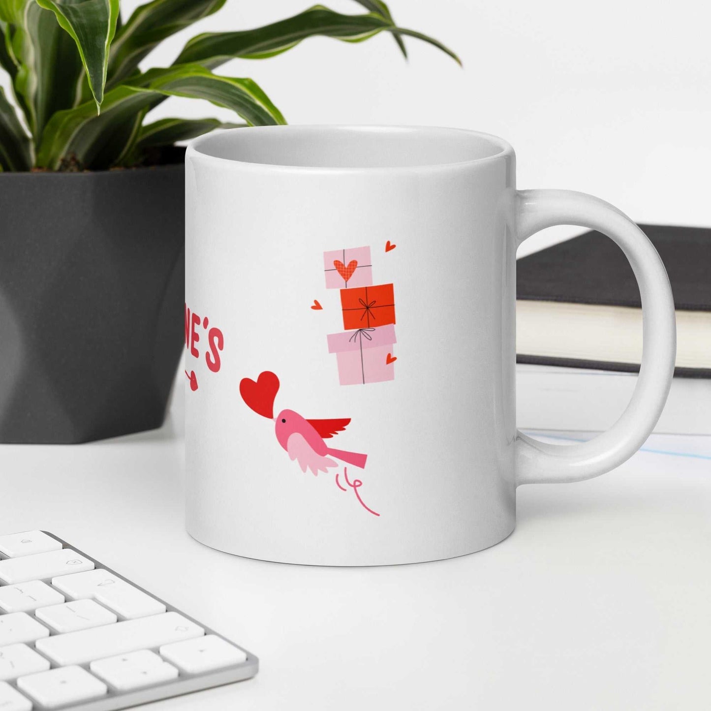 Valentine mug with bird and gift boxes beside keyboard and plant. Great for work-from-home setups.