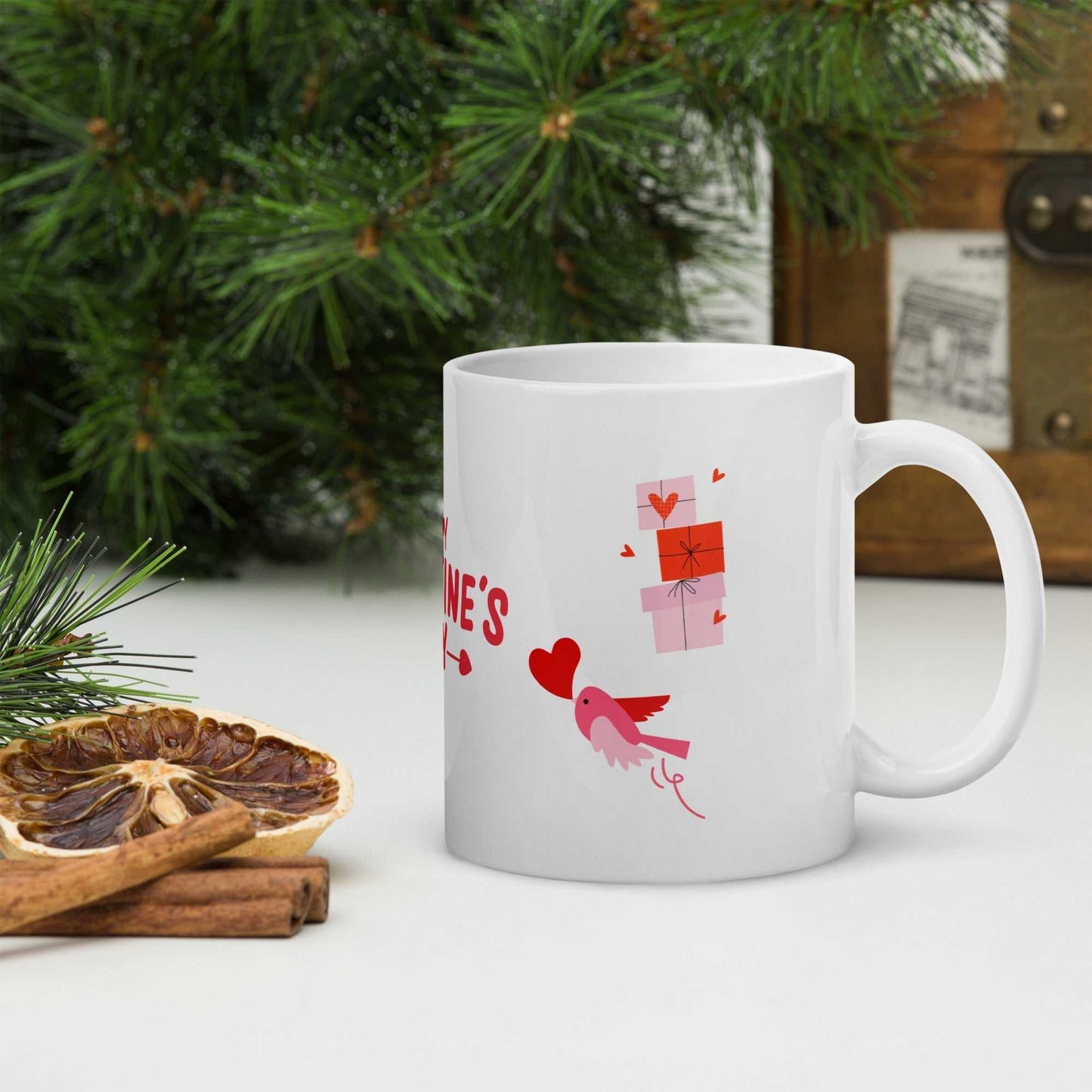 Valentine mug with pink bird and gift boxes, surrounded by festive greenery; perfect for romantic kitchen décor.