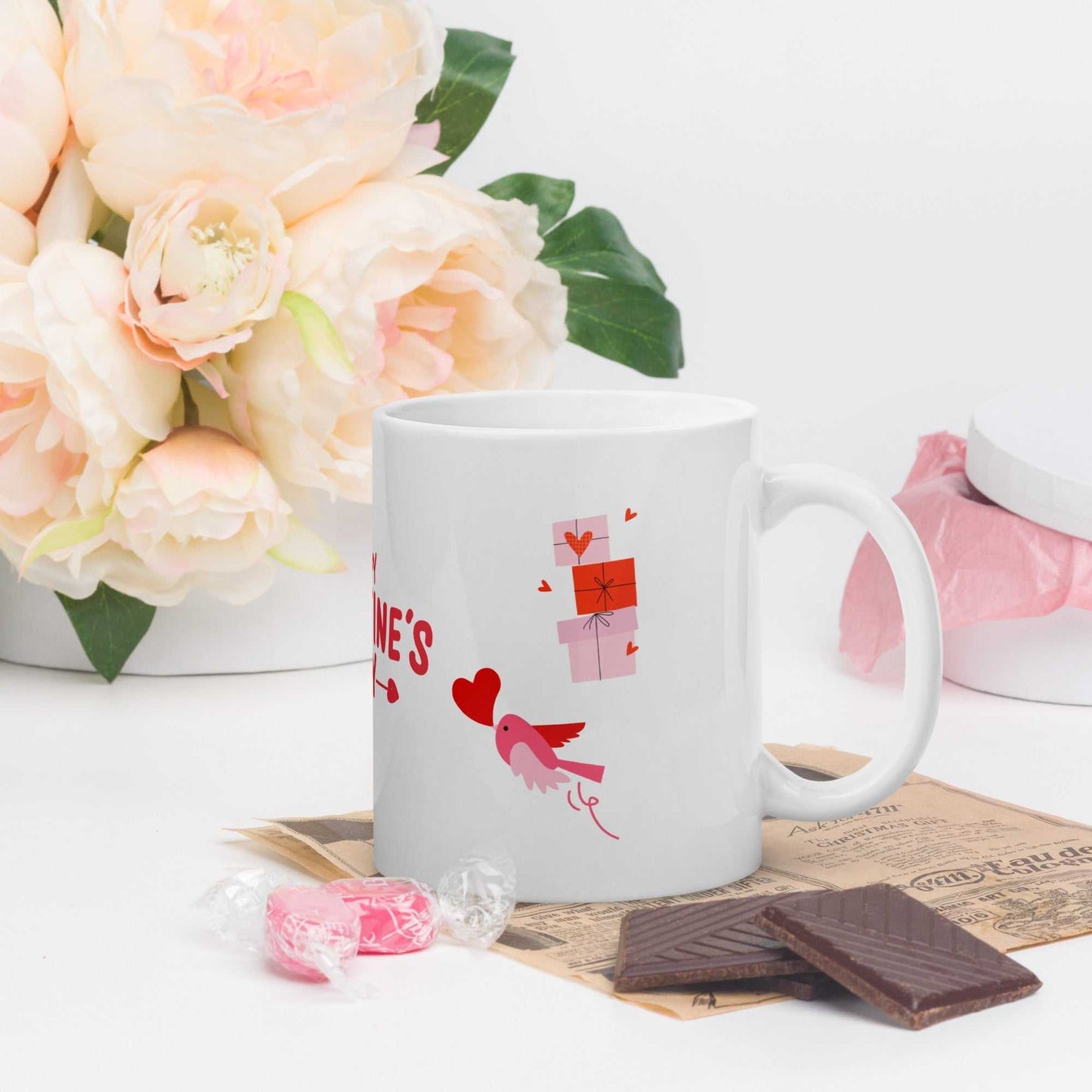 White ceramic mug with pink bird and gift boxes, styled for Valentine's Day gifting; microwave safe and durable.
